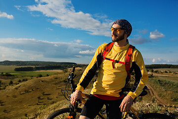 Image showing Cyclist riding a bike on off road to the sunset