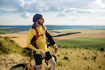 Image showing Cyclist riding a bike on off road to the sunset