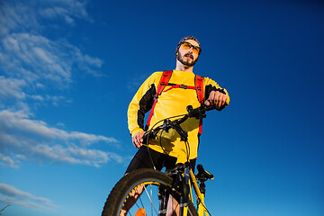 Image showing Cyclist man standing on top of a mountain with bicycle