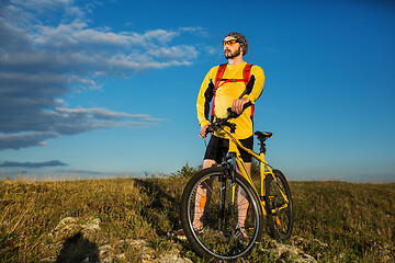 Image showing Cyclist man standing on top of a mountain with bicycle