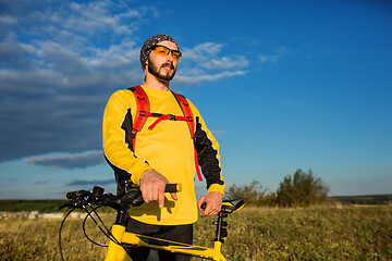 Image showing Cyclist man standing on top of a mountain with bicycle