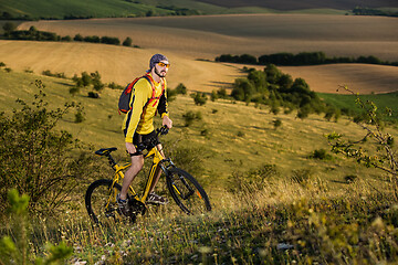 Image showing Young cyclist on a rural road through green spring meadow