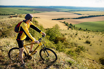 Image showing Cyclist riding a bike on off road to the sunset