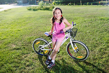 Image showing Portrait of funny girl in pink clothes on her bike