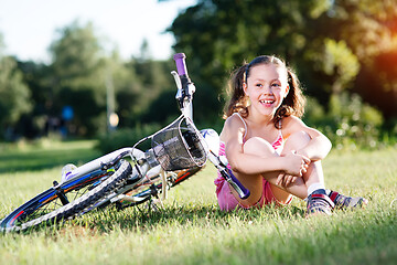 Image showing Portrait of girl with bicycle. Trees on background.