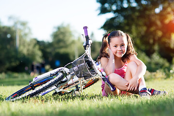 Image showing Portrait of girl with bicycle. Trees on background.