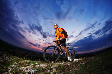 Image showing Man in helmet stay on bicycle under sky with clouds.