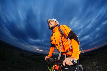 Image showing Man in helmet stay on bicycle under sky with clouds.