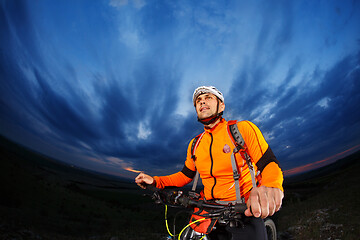 Image showing Man in helmet stay on bicycle under sky with clouds.