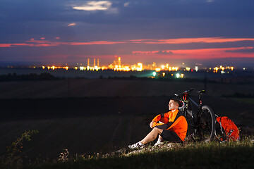 Image showing Cyclist resting on grass in mountains. Man is looking aside.