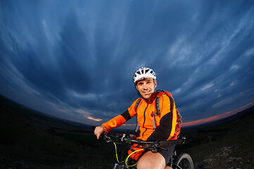 Image showing Man in helmet stay on bicycle under sky with clouds.
