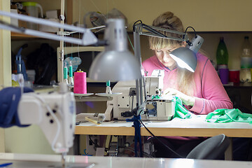 Image showing garment worker at the work desk by the light of the lamp