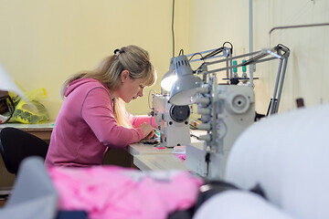 Image showing Worker in sewing workshop sews on a professional sewing machine