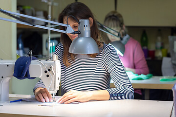 Image showing a seamstress scribbles on a sewing machine in a atelier at her workplace