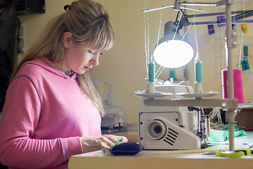 Image showing Girl engaged in needlework at a desk with a sewing machine