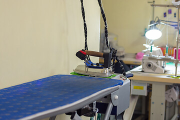 Image showing ironing machine with iron in sewing workshop