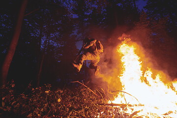 Image showing Soldier in Action at Night jumping over fire