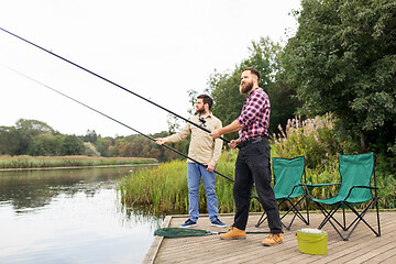 Image showing male friends with fishing rods on lake pier