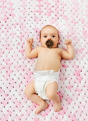 Image showing baby girl in diaper lying with pacifier on blanket