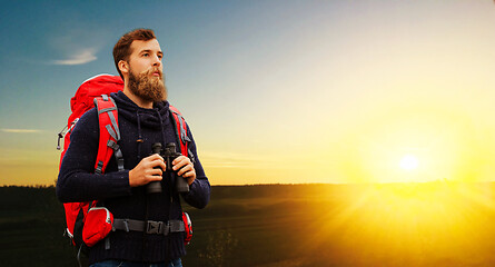 Image showing man with backpack and binocular over sunset