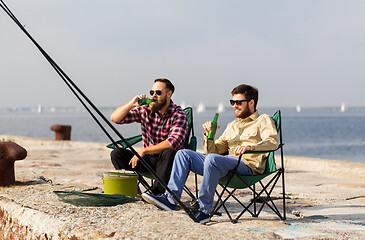 Image showing male friends fishing and drinking beer on pier