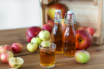 Image showing glass and bottles of apple juice on wooden table