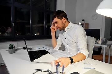 Image showing businessman with papers and laptop at night office