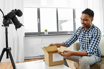 Image showing male video blogger opening parcel box at home