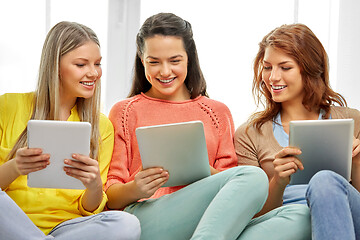 Image showing three smiling teenage girls with tablet pc at home