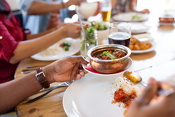 Image showing african man eating with friends at restaurant