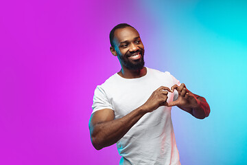 Image showing African-american young man\'s portrait on gradient studio background in neon