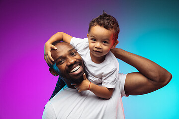 Image showing African-american father and son portrait on gradient studio background in neon