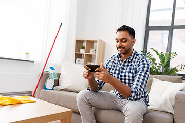 Image showing man playing game on smartphone after cleaning home