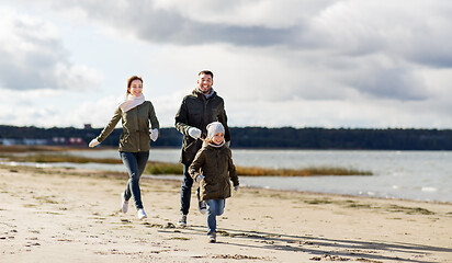 Image showing happy family running along autumn beach