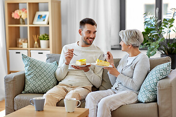 Image showing senior mother and adult son eating cake at home