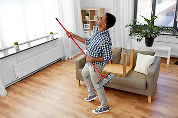 Image showing man with broom cleaning and having fun at home