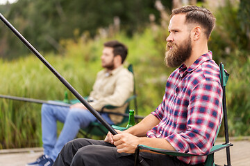 Image showing male friends with fishing rods on lake