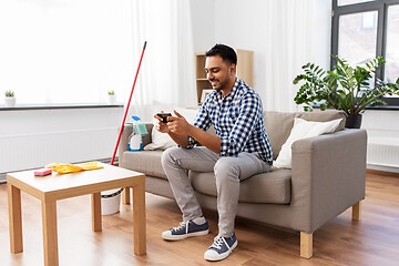 Image showing man playing game on smartphone after cleaning home