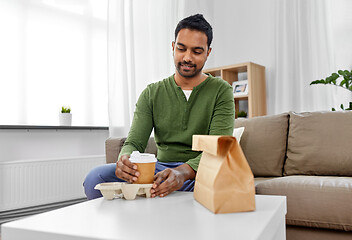 Image showing indian man with takeaway coffee and food at home