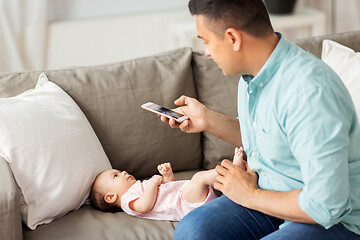 Image showing father with smartphone taking picture baby at home