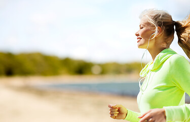 Image showing woman with earphones running at park