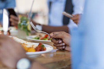 Image showing african man eating with friends at restaurant