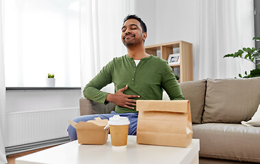 Image showing pleased indian man eating takeaway food at home