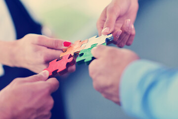 Image showing Group of business people assembling jigsaw puzzle