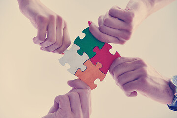 Image showing Group of business people assembling jigsaw puzzle