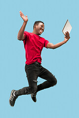 Image showing Image of happy excited young african man jumping isolated over yellow background using laptop