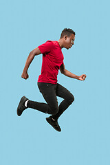 Image showing Freedom in moving and forward motion. The happy surprised young afro man jumping