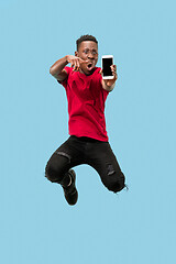 Image showing always on mobile. Full length of handsome young man taking phone while jumping