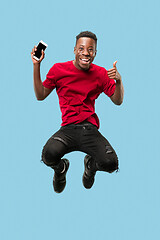 Image showing always on mobile. Full length of handsome young man taking phone while jumping