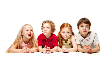 Image showing Close-up of happy children lying on floor in studio and looking up, isolated on white background